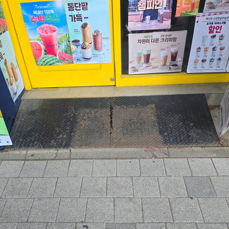 프랜차이즈 카페 출입구 발판 – 정면 · 출입문 앞 전체를 덮은 발판을 정면에서 본 모습